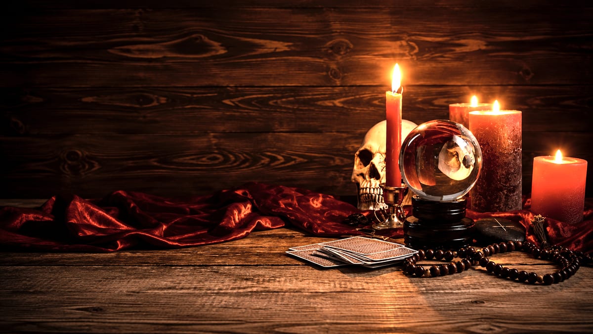 Boule de cristal, cartes et bougies rouges posées sur une table de bois